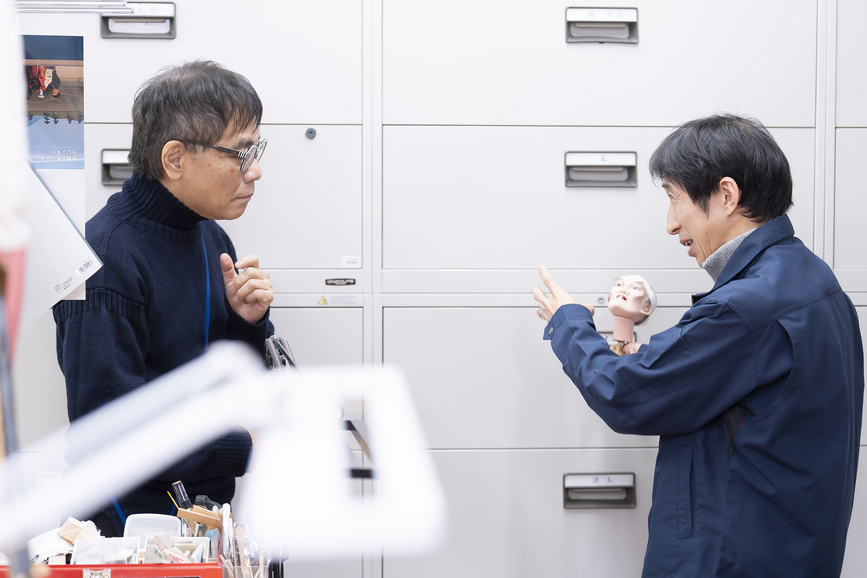 小さなかしらを手にする村尾と説明を聞くいとうせいこう